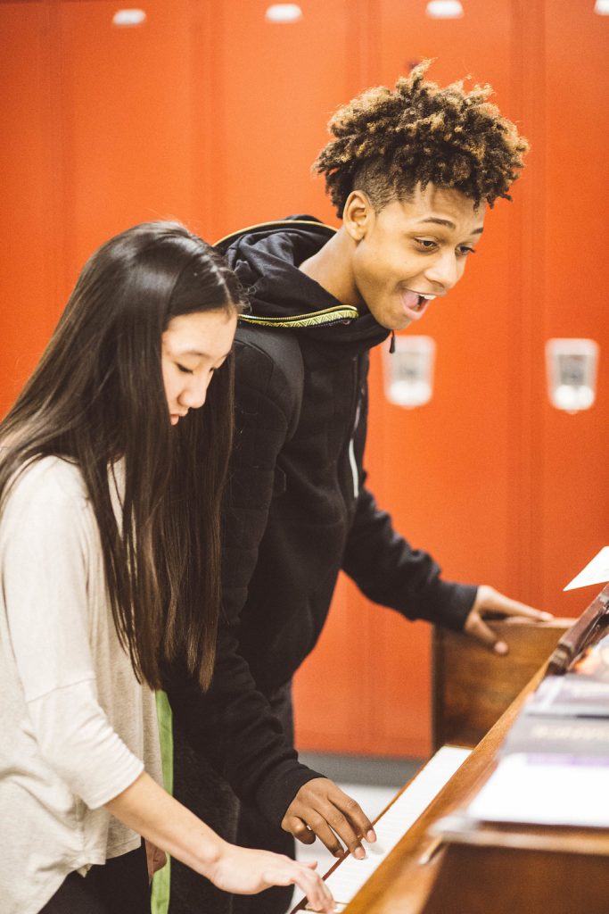 students smiling paying piano