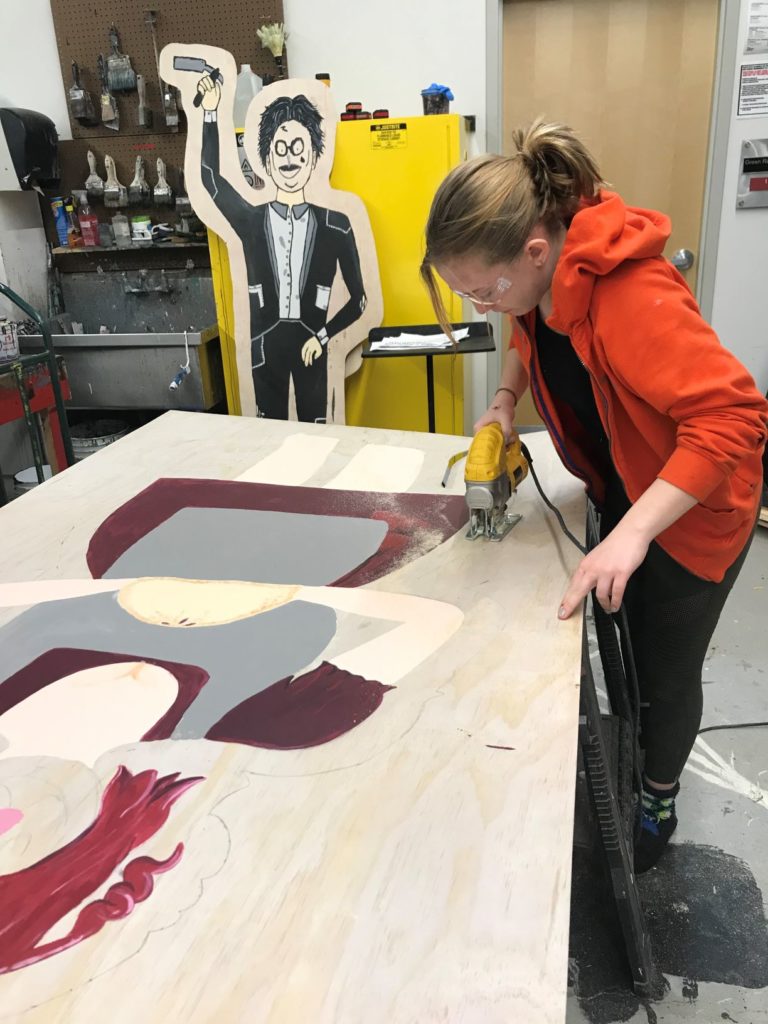 Student cuts out set pieces using a power tool